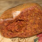 Nduja cut in half and sitting on a wooden plate.