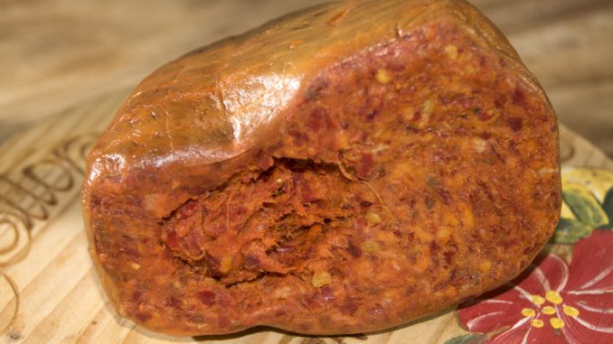 Nduja cut in half and sitting on a wooden plate.