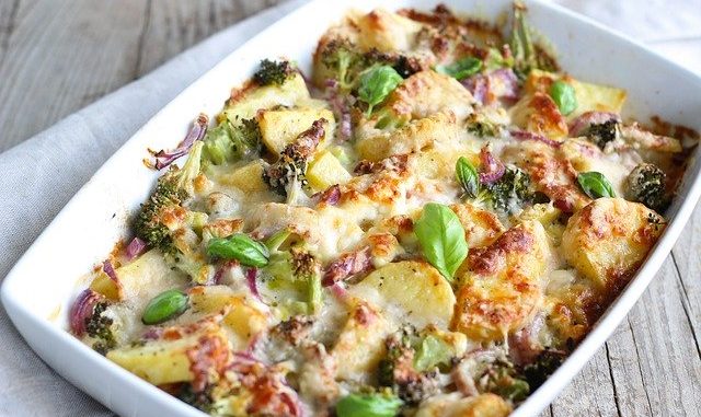Broccoli casserole with cheese and potato in a white dish.