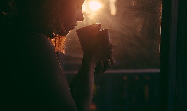 Tea drinker in silhouette aginst a bright early morning Sun.