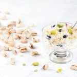 Indian Kheer sweet dessert from rice, nuts and spices in ice cream bowl on white marble table