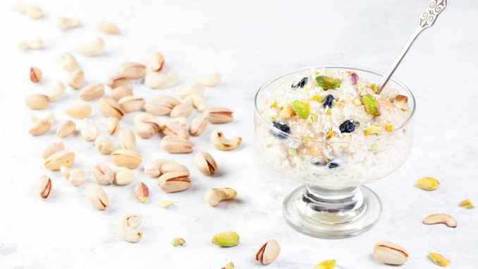 Indian Kheer sweet dessert from rice, nuts and spices in ice cream bowl on white marble table