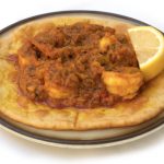 Prawn puri. Prawn puri, a tyical Indian dish, served with a slice of lemon, on a white background