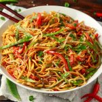 Vegetable Chow mein, noodles and vegetables dish with wooden chopsticks.
