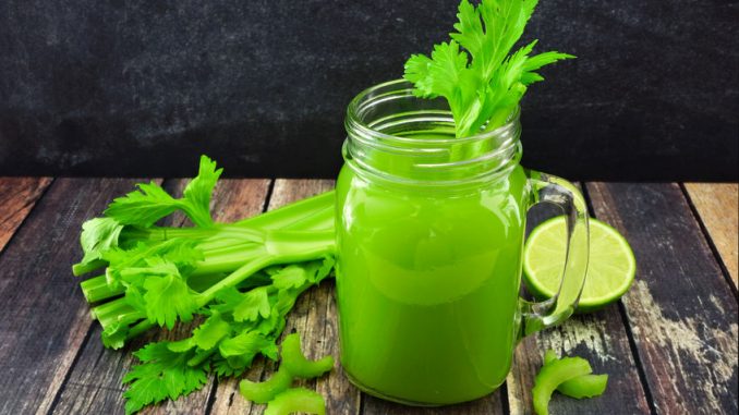 Celery juice in a mason jar glass. Side view over a dark rustic wood background.