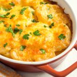 Potato gratin or potato dauphinoise with cream, cheese and parsley in baking dish. Dauphinoise Potatoes