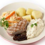 Veal sirloin steak with onion marmalade, celeriac puree, julienned carrots in a white sauce and boiled potatoes, garnished with parsley.