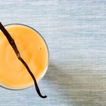 Bowl of homemade vanilla custard (creme anglaise) on blue background. Top view. Copyspace.