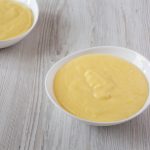 Homemade vanilla custard in bowls over white wooden background , low angle view. Close-up.