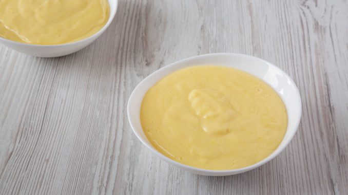 Homemade vanilla custard in bowls over white wooden background , low angle view. Close-up.