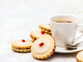 Empire biscuits on a white background with a cup of tea or coffee.