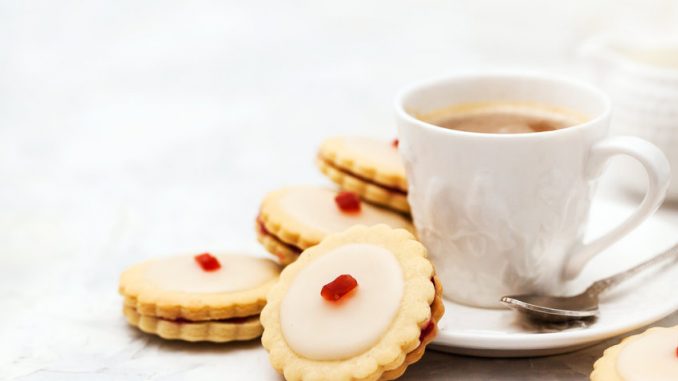 Empire biscuits on a white background with a cup of tea or coffee.