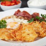 Hash browns, potato pancakes with poached egg and streaky bacon.