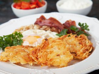 Hash browns, potato pancakes with poached egg and streaky bacon.