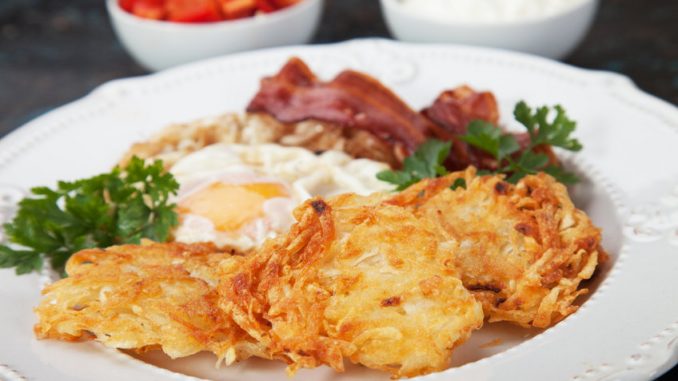 Hash browns, potato pancakes with poached egg and streaky bacon.