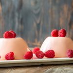 Panna cotta desserts decorated with fresh raspberries.