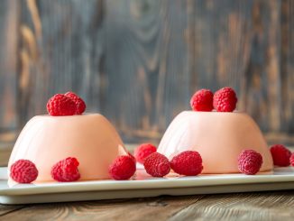 Panna cotta desserts decorated with fresh raspberries.