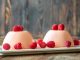 Panna cotta desserts decorated with fresh raspberries.