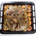 Cooked Whole Turbot fish in baking pan oven with potatoes olives and aromatic herbs isolated on white background