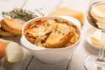 French onion soup with its ingredients on the white table (traditional cuisine).