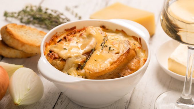 French onion soup with its ingredients on the white table (traditional cuisine).