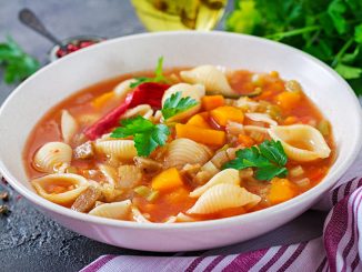 Minestrone, Italian vegetable soup with pasta on table. Vegan food.