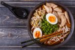 Japanese ramen soup with chicken, egg, chives and sprout on dark wooden background.