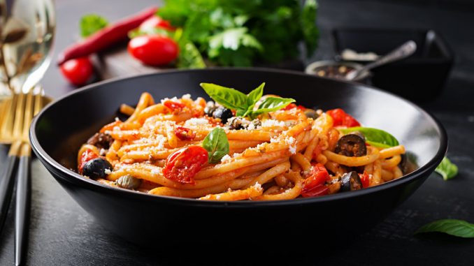 Spaghetti alla puttanesca - italian pasta dish with tomatoes, black olives, capers, anchovies and basil