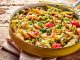 Gourmet seafood Italian tagliatelle pasta with shrimp, tomato, spinach and garlic served on a rustic wooden table in a yellow frying pan, high angle view