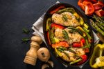 Baked chicken breasts (fillet) with vegetables. Healthy food, keto diet, one pot dish. Top view at dark table.