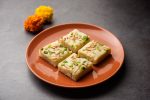 milk burfi (khoya burfi) on brown plate, dark background.