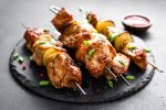 Grilled meat skewers, shish kebabs on black background
