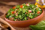 A bowl of delicious fresh tabouli with parsley, mint, tomato, onion, olive oil, lemon juice, and bulgar wheat.