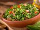 A bowl of delicious fresh tabouli with parsley, mint, tomato, onion, olive oil, lemon juice, and bulgar wheat.
