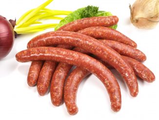 making sausages: sausages on a white background with a red onion in partial view.