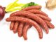making sausages: sausages on a white background with a red onion in partial view.