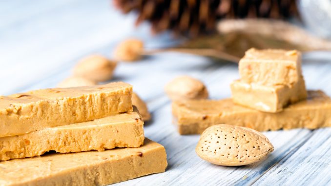Turrón is a traditional Spanish sweets. Decorations of almonds on wooden table.