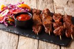 Nigerian barbecue: suya on skewers with fresh vegetable salad and ketchup close-up on the table. horizontal