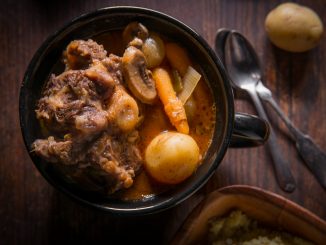 Potjiekos South African oxtail stew with baby gold potatoes carrots and button mushrooms.