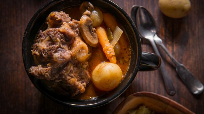 Potjiekos South African oxtail stew with baby gold potatoes carrots and button mushrooms.