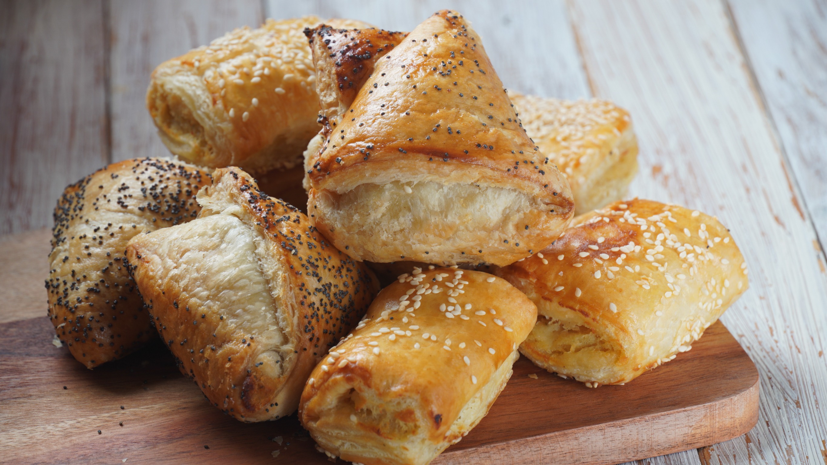 Burekas with cheese and mushrooms, potato. Israeli Savory Pastries. Baked pastry with poppy seeds and sesame on a wooden background
