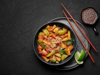 Penang Rojak in black bowl on dark slate table top. Malaysian or indonesian cuisine fruits and vegetables salad dish. Asian Food. Korean traditional food Stir-fried sweet potato with sesame seeds. Top view. Copy space
