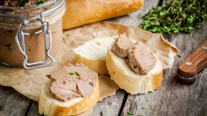 homemade chicken liver pate with fresh baguette and thyme on rustic wooden table