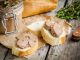 homemade chicken liver pate with fresh baguette and thyme on rustic wooden table