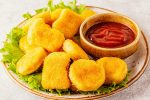 Crispy fried chicken nuggets with ketchup on a plate.