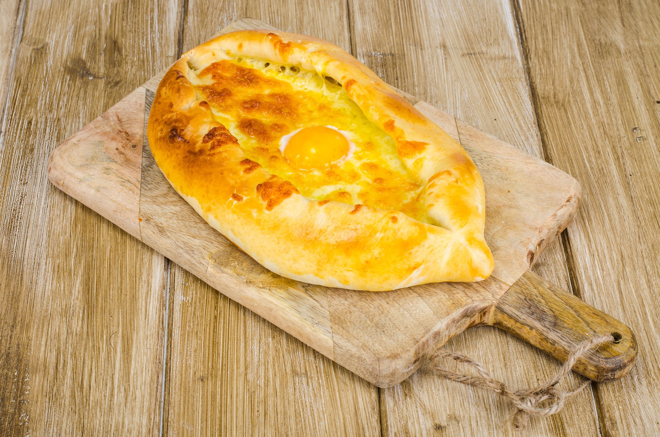 Hot khachapuri with cheese and egg on wooden board