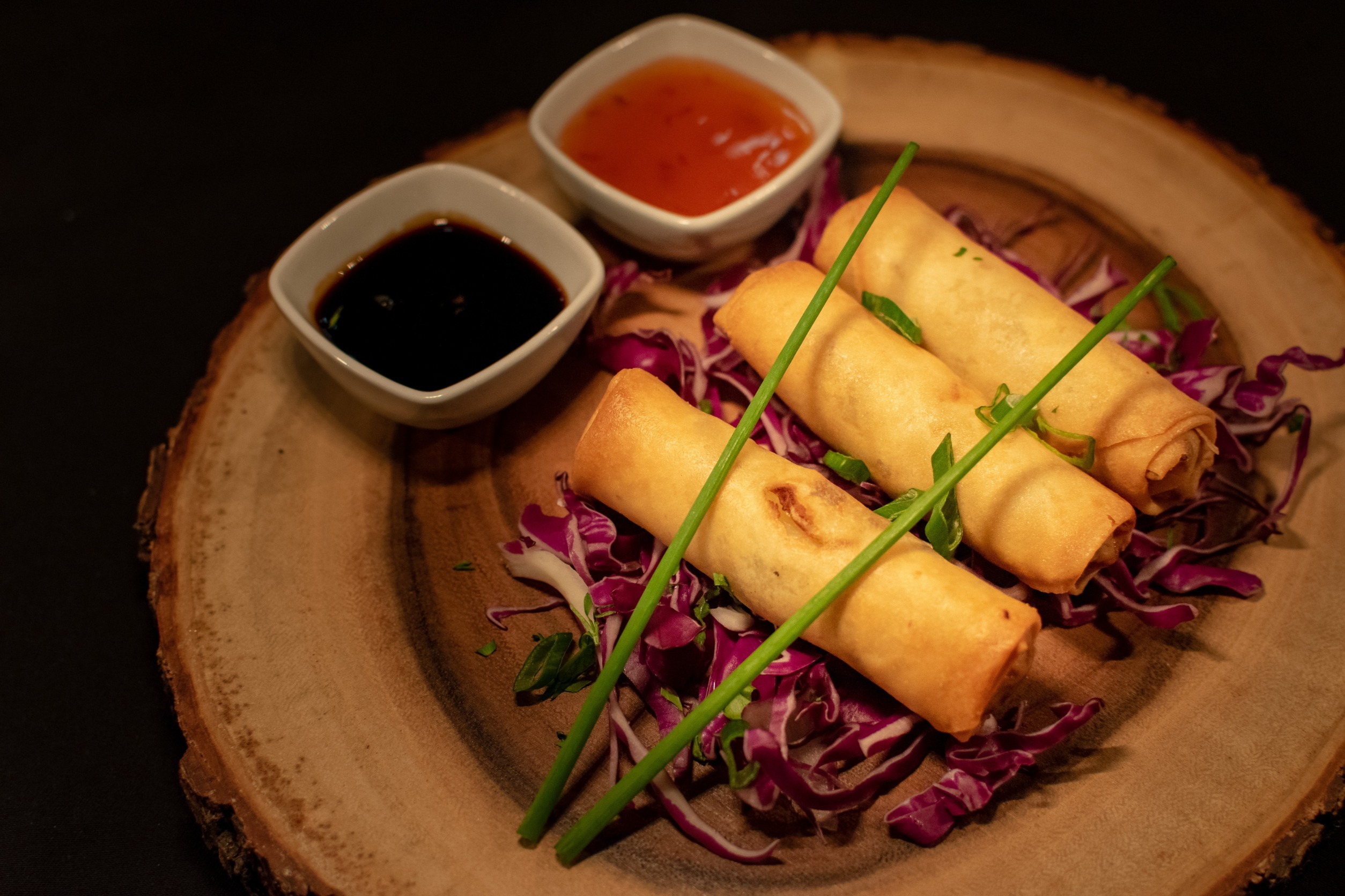 Chun Juan Spring Rolls on a plate with various dipping sauces.