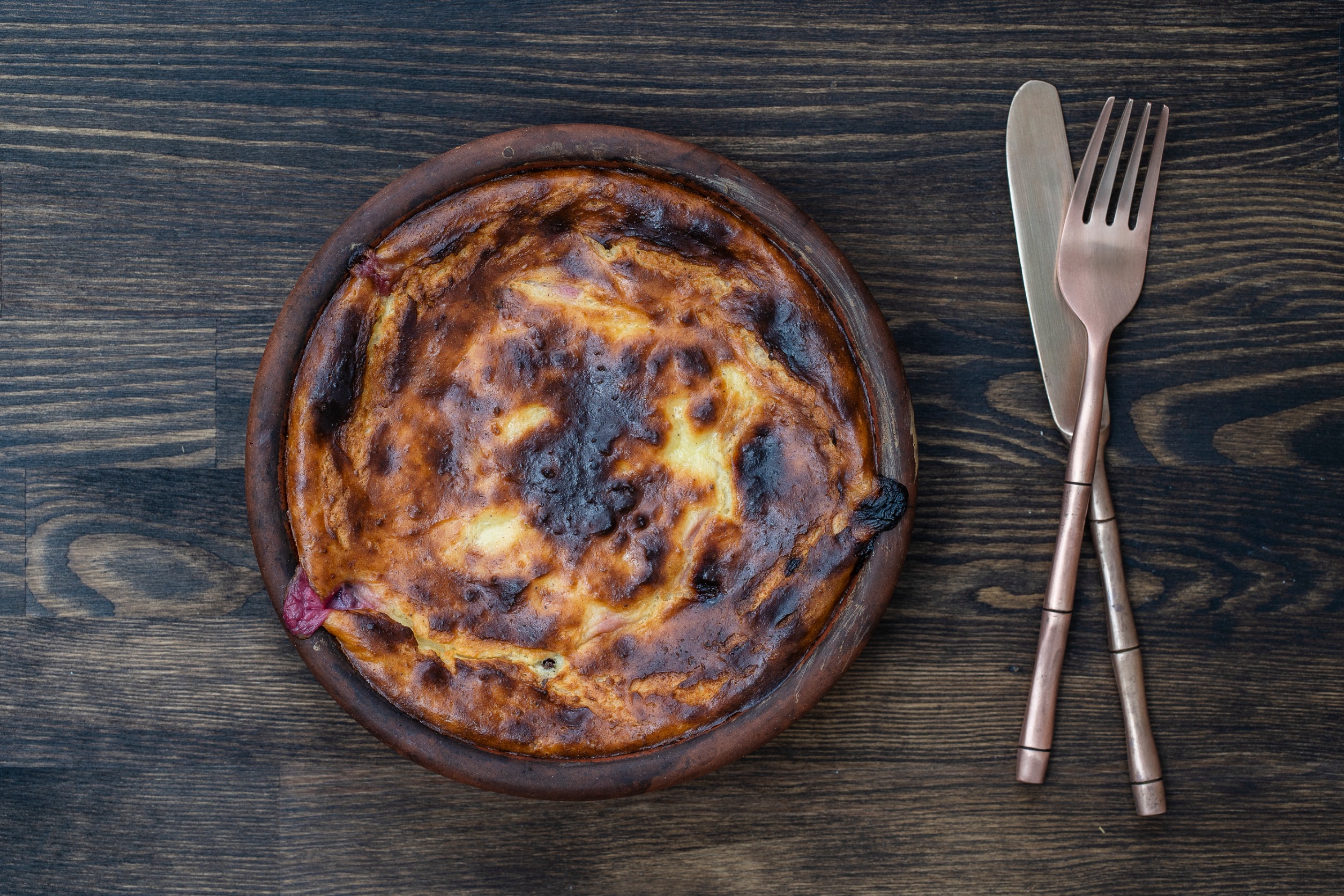 Sweet cottage cheese casserole with raisins and semolina on wooden table. Ceramic bowl with baked cottage cheese casserole, close up, top view