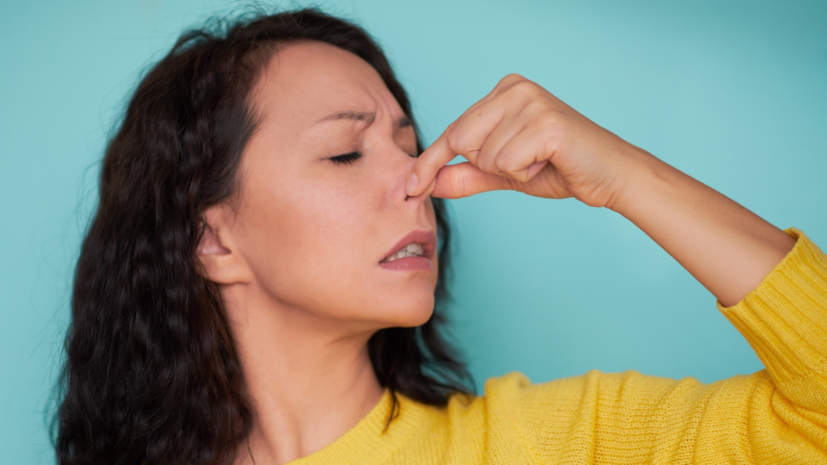 Young woman holding a nose because of nasty off-flavours, off-aroma.