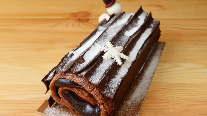 Delectable Buche de Noel or Chocolate Yule Log Cake for Christmas Sprinkle with Icing Sugar on the Wooden Table